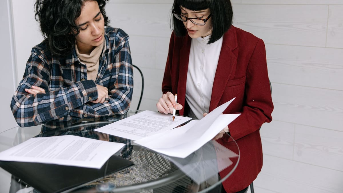 Duas pessoas à mesa revisando documentos de contrato juntas