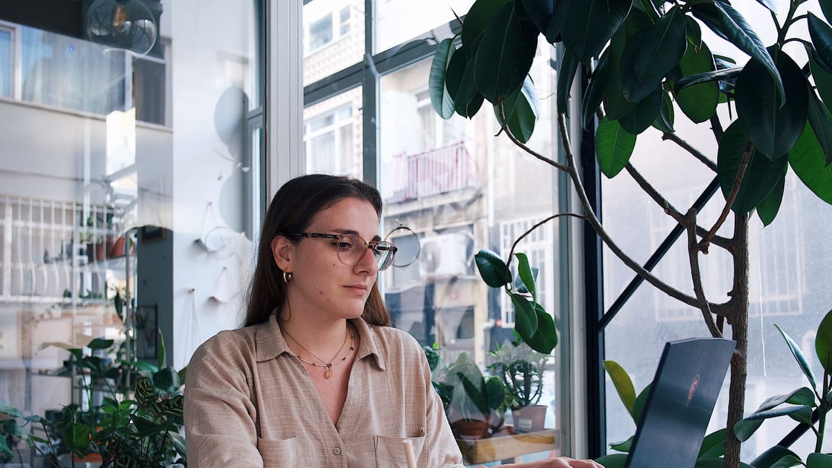 A freelancer working on a laptop at a cafe window